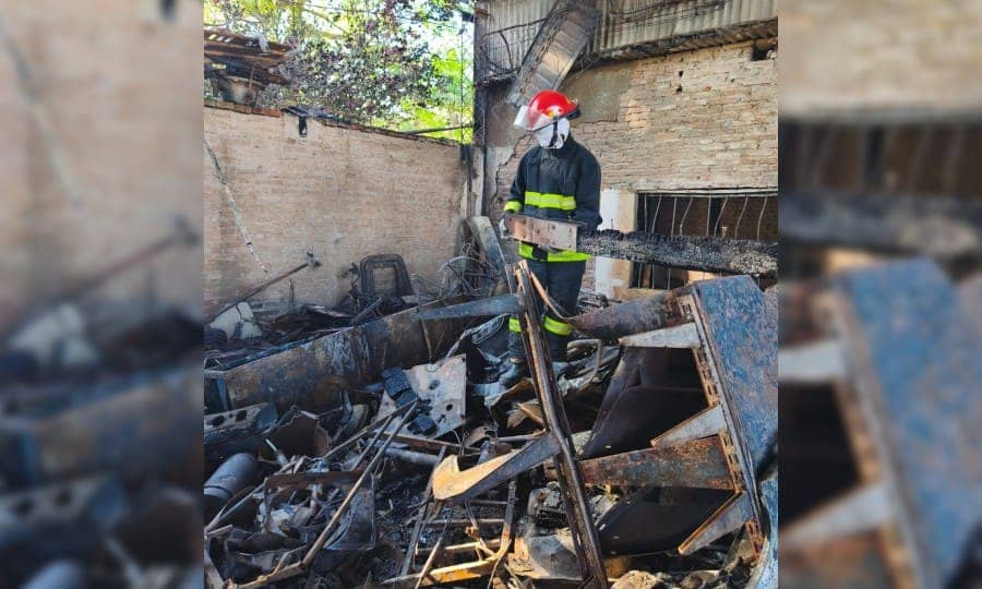 A firefighter in a red helmet among the debris, by day.